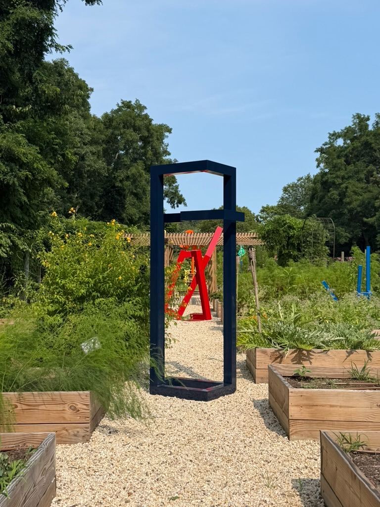Navy frame sculpture on the gravel path
